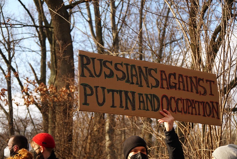 Man holding sign reading: Russians Against Putin and Occupation