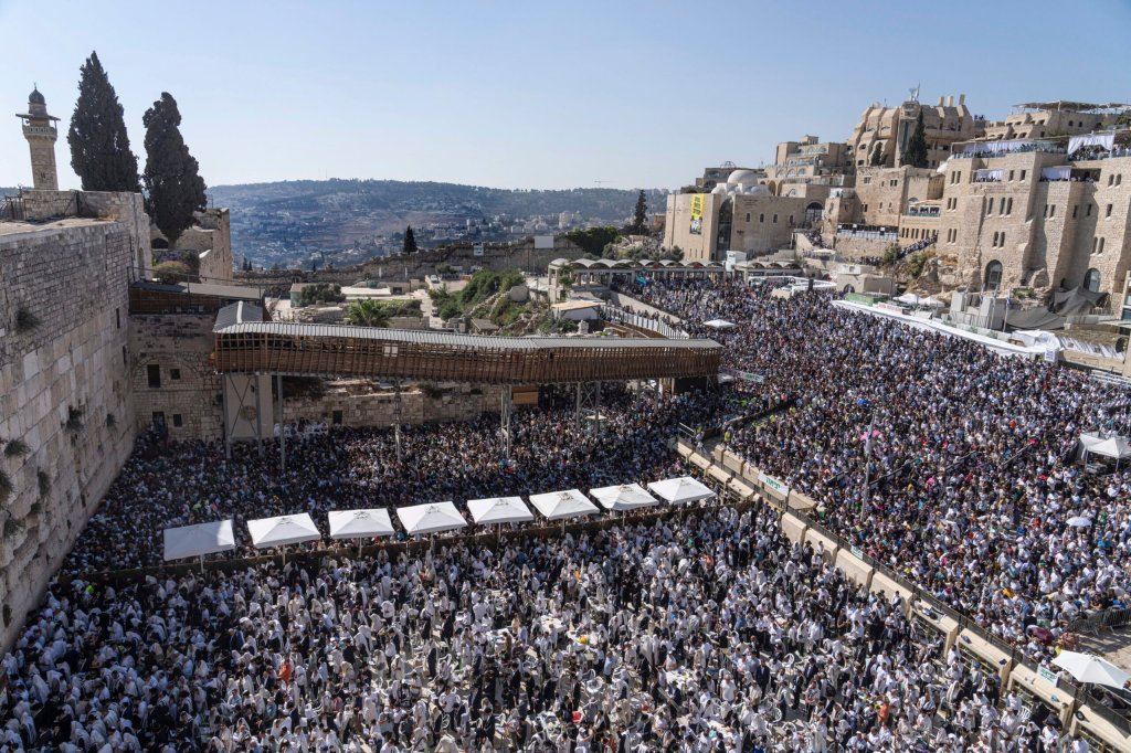 An aerial view of the Western Wall in the Old City of Jerusalem, where many figures are seen praying below during Sukkot.