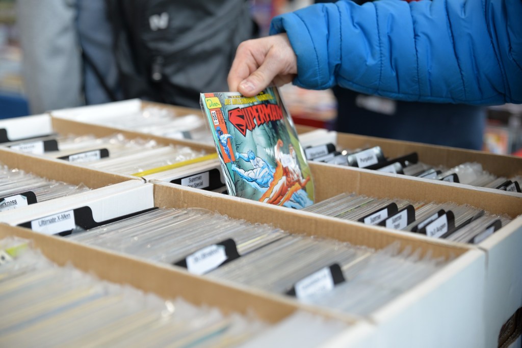 A person's hand pulling a "Superman" comic out of a box.