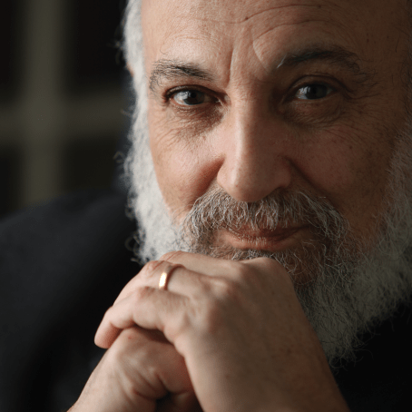 Harold Kasimow posing with his hands folded, looking directly at the camera.